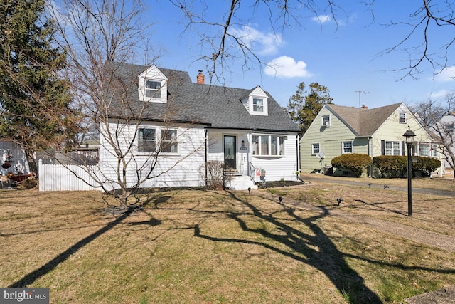 cape cod-style house featuring a shingled roof, entry steps, a chimney, and a front lawn