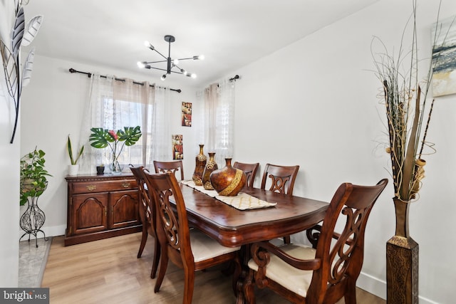 dining room featuring baseboards, light wood-style flooring, and an inviting chandelier