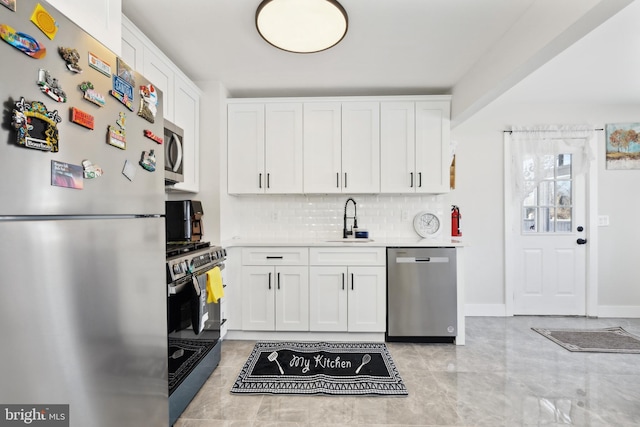 kitchen with appliances with stainless steel finishes, white cabinets, light countertops, and a sink