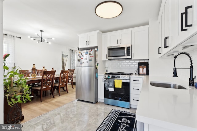 kitchen with a chandelier, a sink, white cabinetry, appliances with stainless steel finishes, and tasteful backsplash