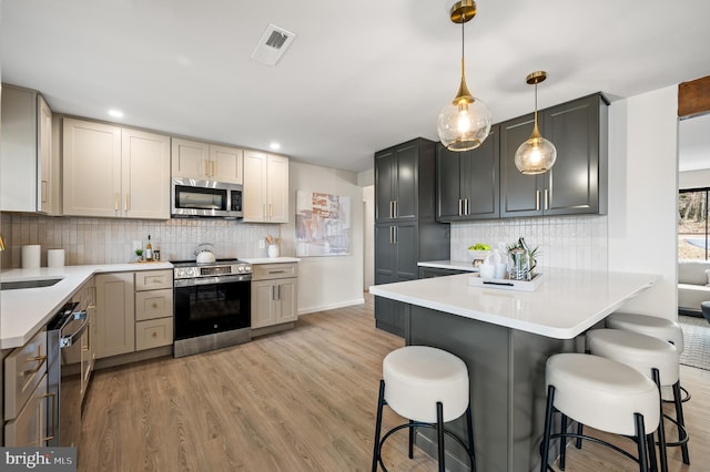 kitchen featuring visible vents, a breakfast bar, stainless steel appliances, light countertops, and light wood-type flooring