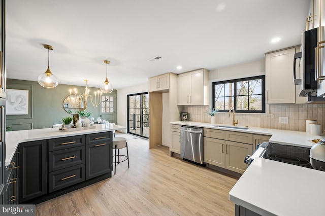 kitchen with light countertops, visible vents, appliances with stainless steel finishes, a sink, and light wood-type flooring