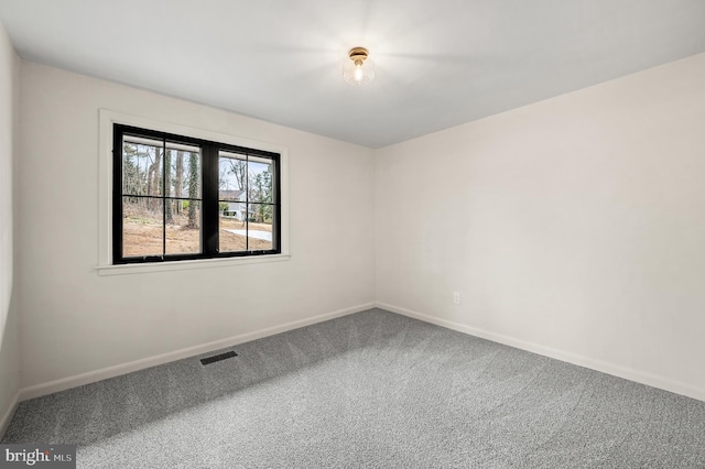 carpeted spare room featuring baseboards and visible vents