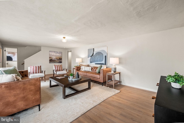 living room with a textured ceiling, baseboards, and wood finished floors