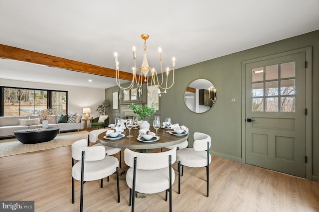 dining room with baseboards, light wood-type flooring, beam ceiling, and a notable chandelier