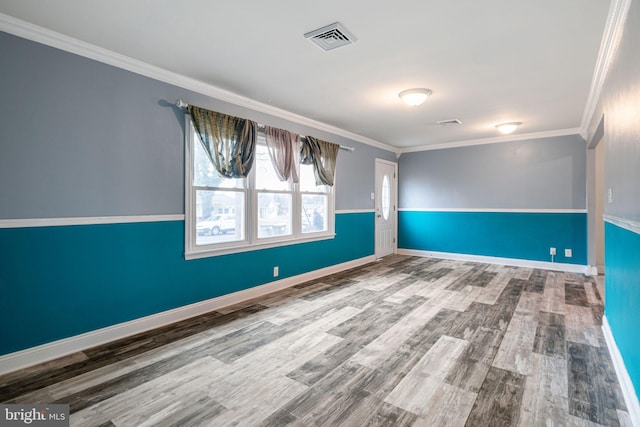 unfurnished room with ornamental molding, a wainscoted wall, visible vents, and wood finished floors