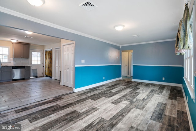 spare room with ornamental molding, visible vents, baseboards, and wood finished floors