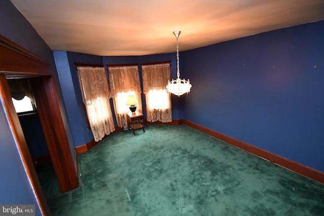 unfurnished dining area featuring carpet floors, baseboards, and a chandelier