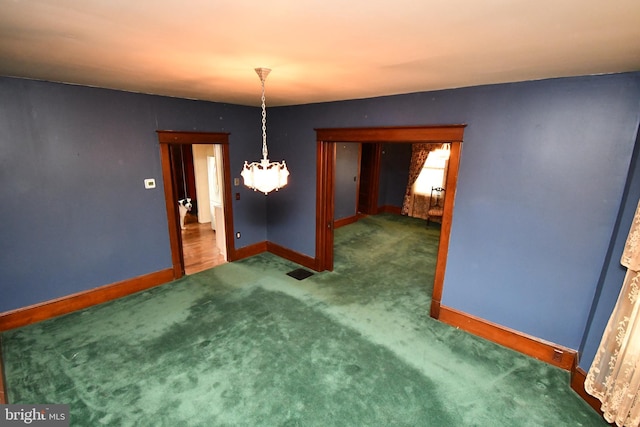 unfurnished dining area featuring a chandelier, baseboards, and carpet flooring