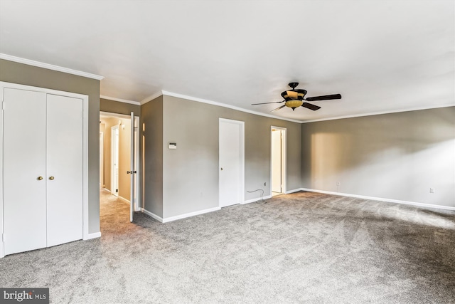 unfurnished bedroom featuring a ceiling fan, carpet, crown molding, and baseboards