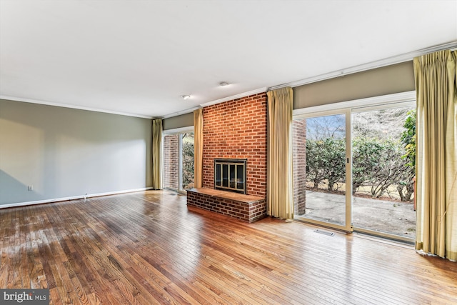 unfurnished living room featuring a healthy amount of sunlight, wood-type flooring, a fireplace, and ornamental molding