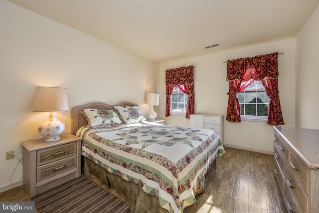 bedroom with wood finished floors, visible vents, and baseboards