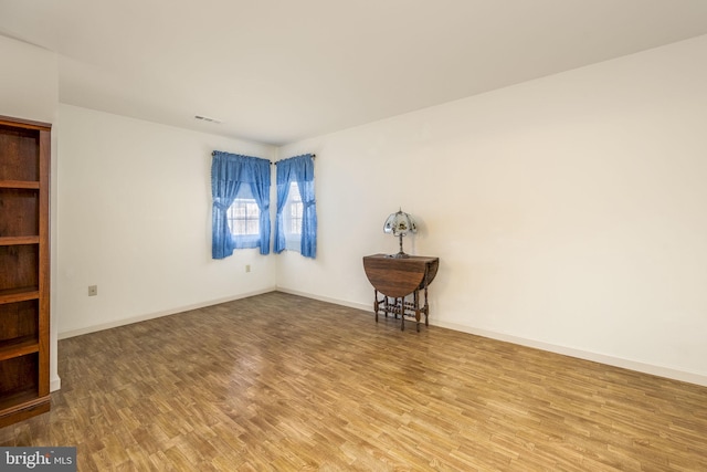 empty room with baseboards, visible vents, and wood finished floors