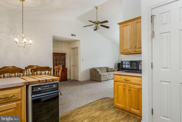 kitchen featuring light countertops, visible vents, open floor plan, black microwave, and ceiling fan with notable chandelier