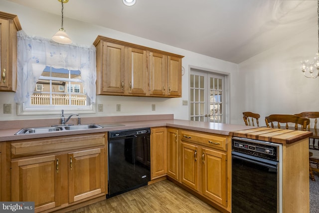 kitchen featuring black dishwasher, lofted ceiling, light wood-style flooring, a sink, and a peninsula