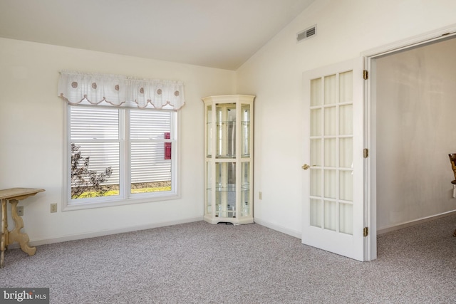 spare room with lofted ceiling, baseboards, visible vents, and carpet