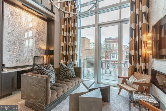 living area with a view of city, a high ceiling, a wall of windows, and wood finished floors