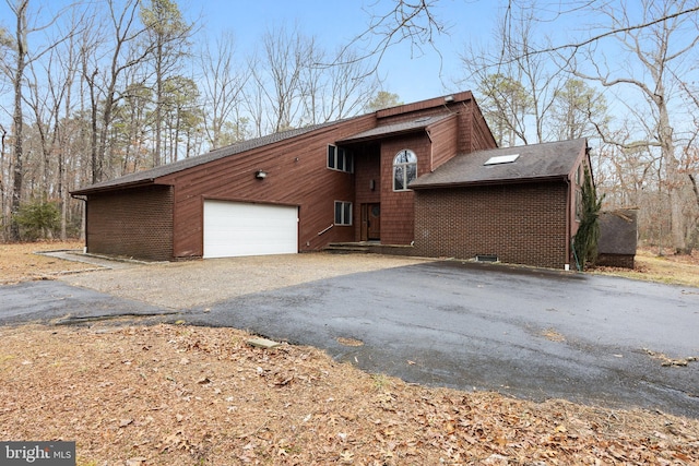 view of side of home with driveway, brick siding, roof with shingles, and an attached garage