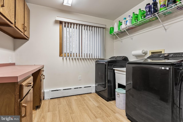 washroom with a baseboard heating unit, light wood finished floors, and washing machine and clothes dryer