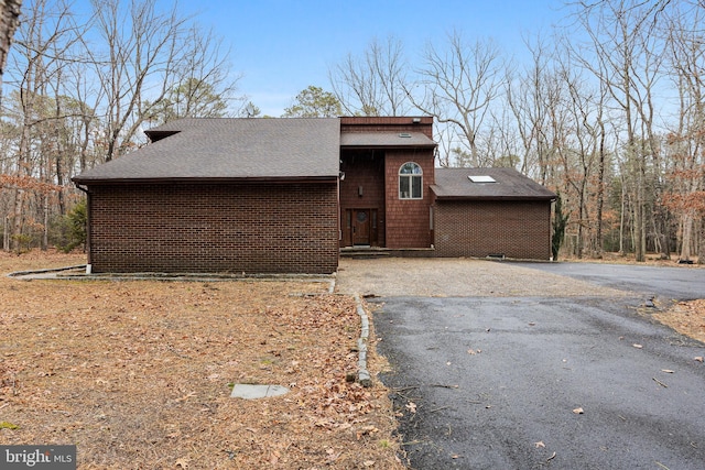 view of front facade with driveway and roof with shingles