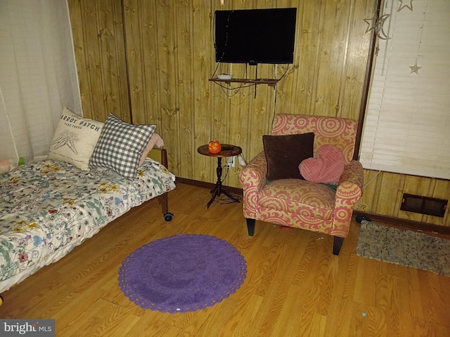 bedroom with wood finished floors, visible vents, and wood walls