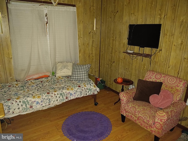 bedroom featuring wood finished floors and wood walls