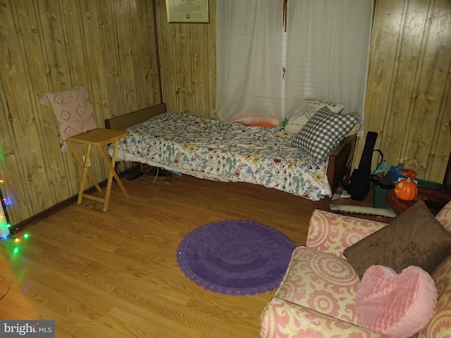 bedroom with wood finished floors and wood walls