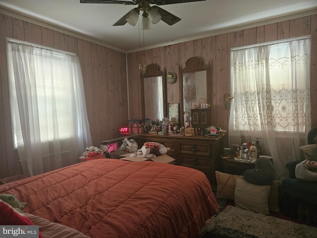 bedroom featuring multiple windows, wood walls, and crown molding