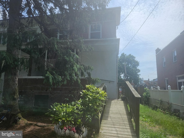 view of side of home with brick siding and fence