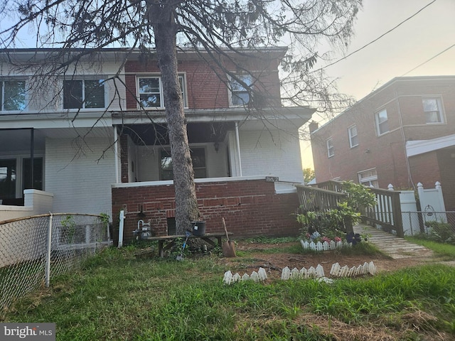 exterior space featuring brick siding, a porch, and fence