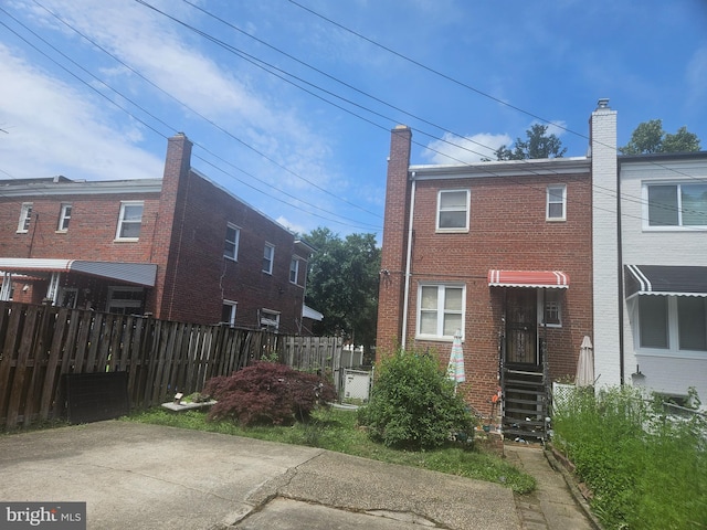 rear view of house featuring brick siding and fence