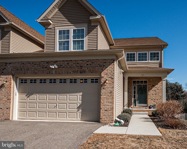 traditional home featuring a garage, aphalt driveway, and brick siding