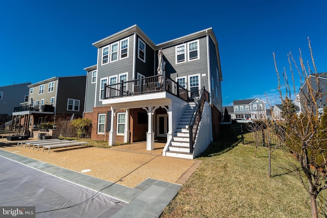 view of front of house with brick siding, fence, stairs, a residential view, and a front lawn