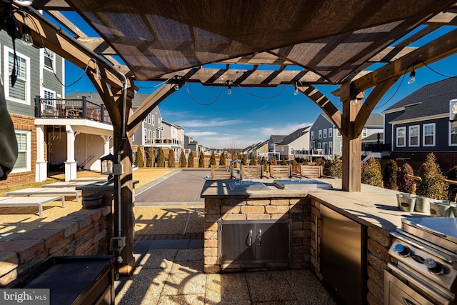 view of patio featuring an outdoor kitchen, fence, a residential view, and a pergola