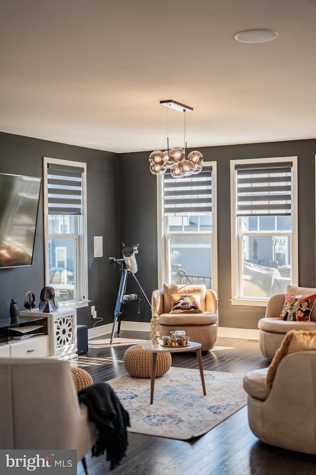 sitting room with a notable chandelier, baseboards, and wood finished floors