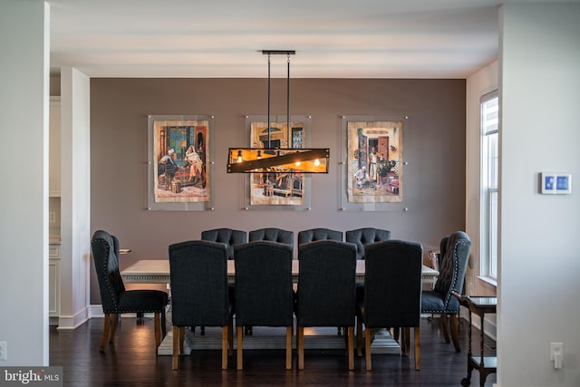 dining space featuring a chandelier, dark wood-type flooring, and baseboards