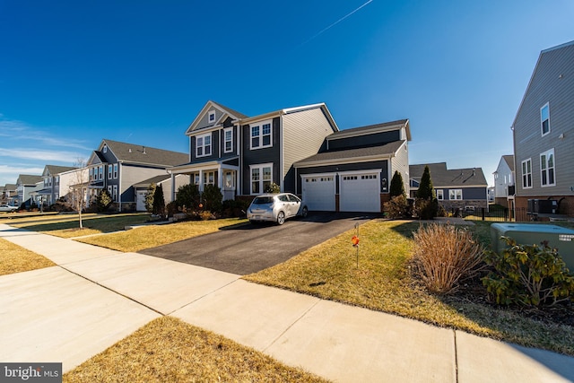 view of front facade with an attached garage, a residential view, aphalt driveway, and a front yard