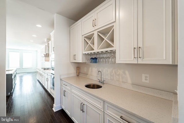 bar with dark wood-style floors, appliances with stainless steel finishes, wet bar, a sink, and recessed lighting