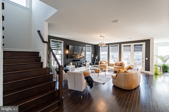 living area with a healthy amount of sunlight, stairway, hardwood / wood-style floors, and an inviting chandelier