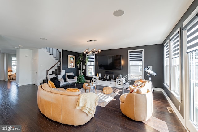 living room featuring baseboards, visible vents, dark wood-style floors, stairs, and a notable chandelier