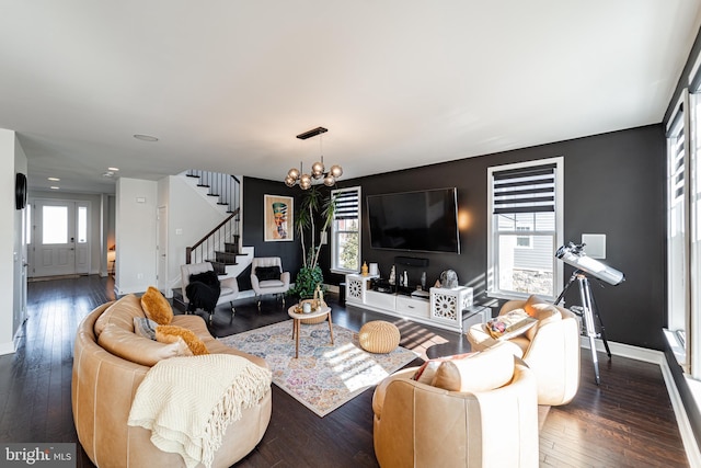 living room featuring baseboards, hardwood / wood-style floors, stairway, and an inviting chandelier