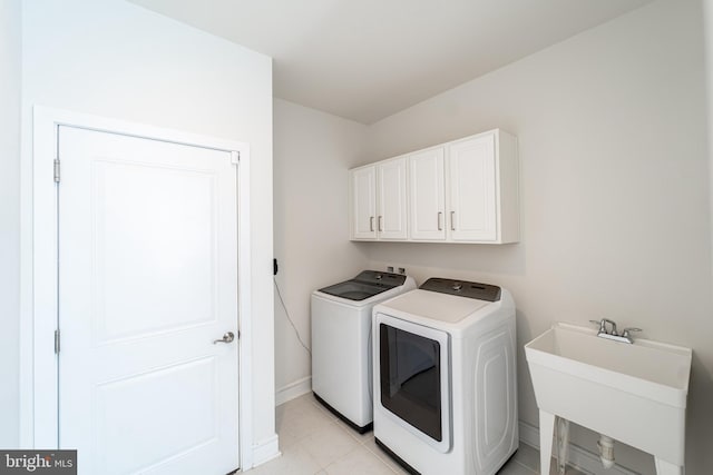 laundry room with light tile patterned floors, cabinet space, a sink, independent washer and dryer, and baseboards