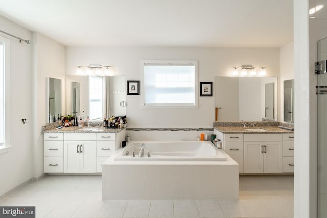 full bath with two vanities, tile patterned flooring, a garden tub, and a sink