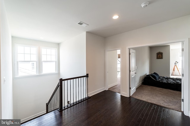 hall with baseboards, visible vents, dark wood-type flooring, an upstairs landing, and recessed lighting