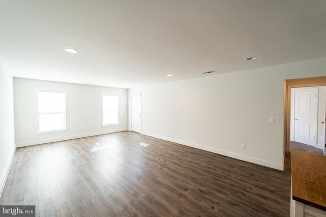 spare room with baseboards, visible vents, dark wood-style flooring, and recessed lighting