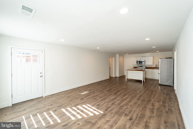 unfurnished living room with wood finished floors, visible vents, and recessed lighting