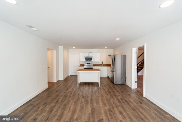 kitchen with visible vents, white cabinets, baseboards, appliances with stainless steel finishes, and dark wood-style flooring