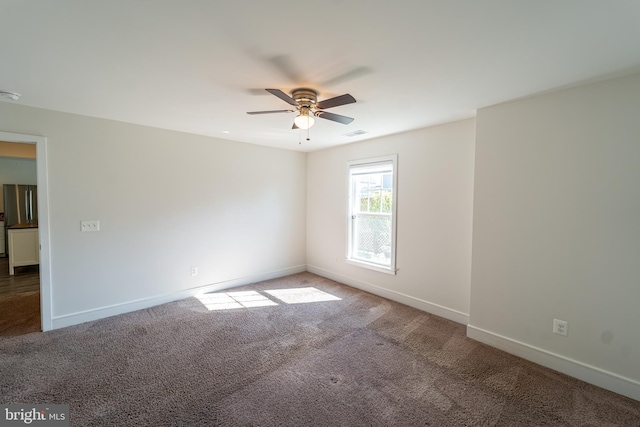 unfurnished room with carpet, visible vents, baseboards, and a ceiling fan