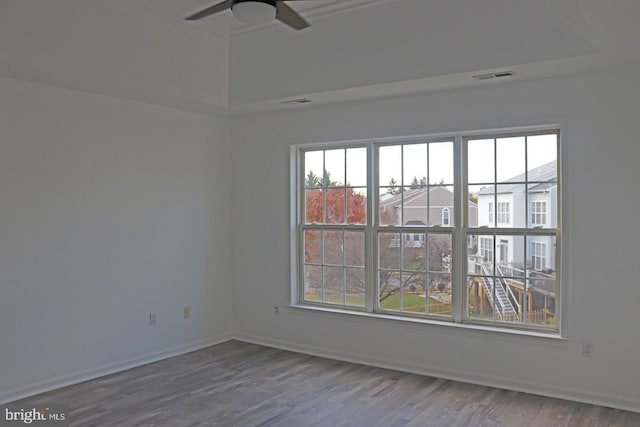 spare room with baseboards, wood finished floors, visible vents, and a ceiling fan