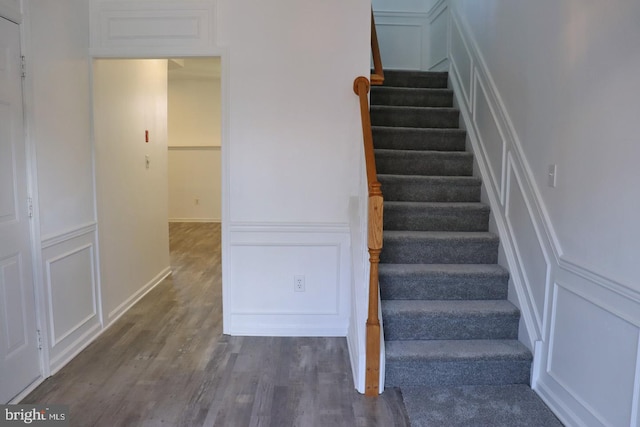 staircase with wood finished floors and a decorative wall